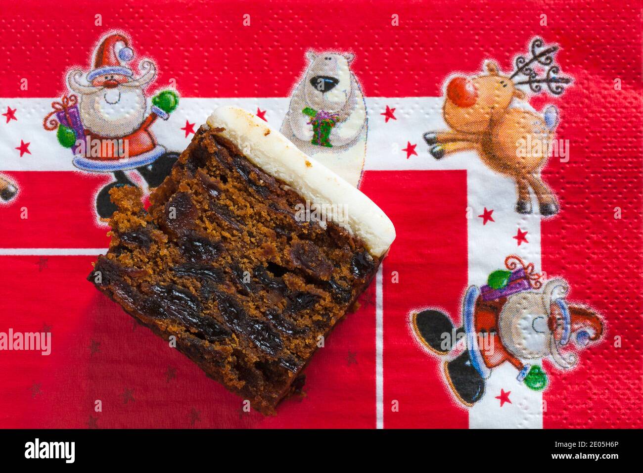 Slice of M&S Iced Fruit Cake Christmas Cake set on red Christmas serviette napkin - UK festive Xmas Stock Photo
