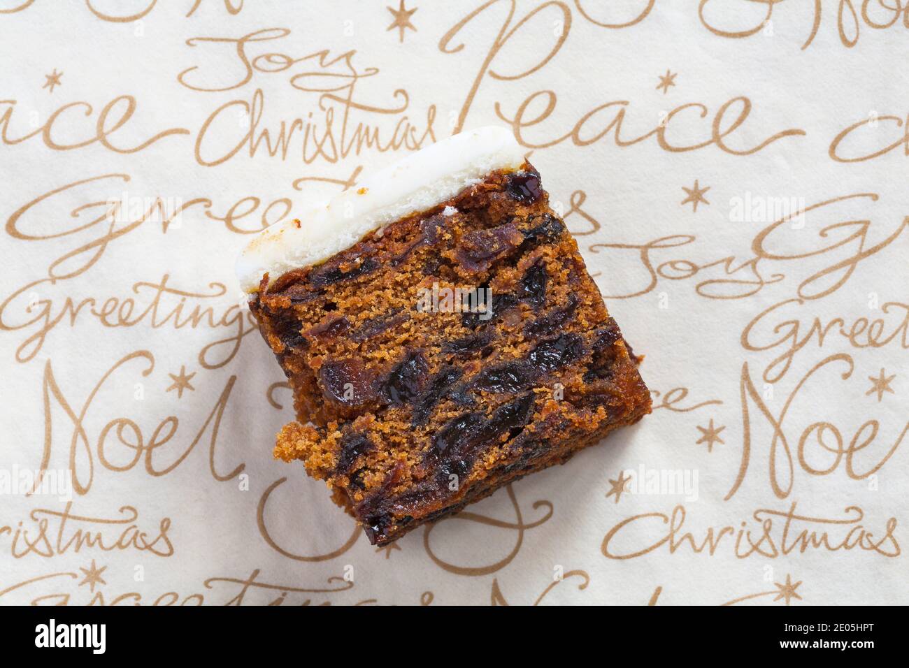 Slice of M&S Iced Fruit Cake Christmas Cake set on Christmas serviette napkin - UK festive Xmas Stock Photo