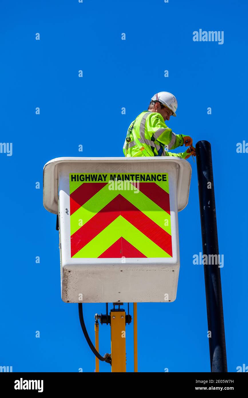 London, UK, July 14, 2014 :  A male highway maintenance worker in a mobile crane scissor lift repairing and fixing a street lamp post, stock photo ima Stock Photo