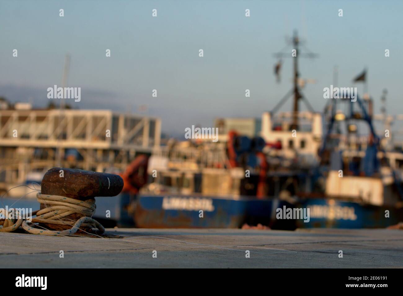 Anchor pole dock with ship vessels docked in the background Stock Photo