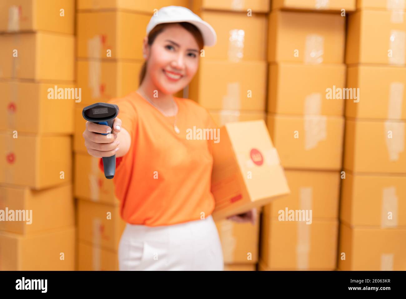Asian parcel delivery worker in warehouse with barcode scanner. Stock Photo