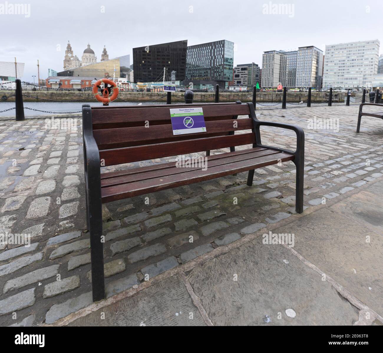 A bench in the Royal Albert Dock area of Liverpool with a sign on saying that it is currently unavailable but doesn't explain why Stock Photo