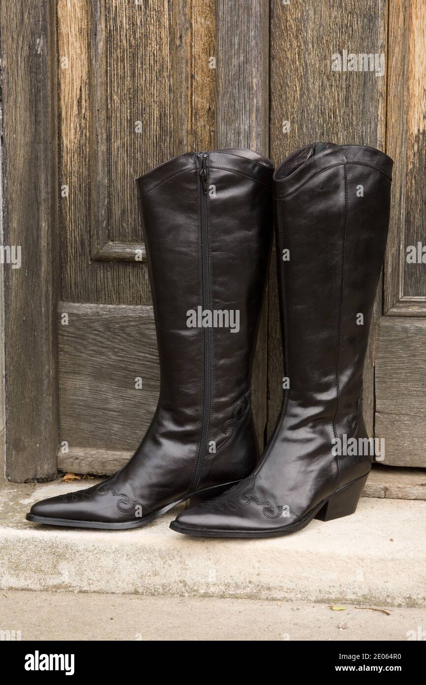 Ladies black leather boots standing front door step Stock Photo