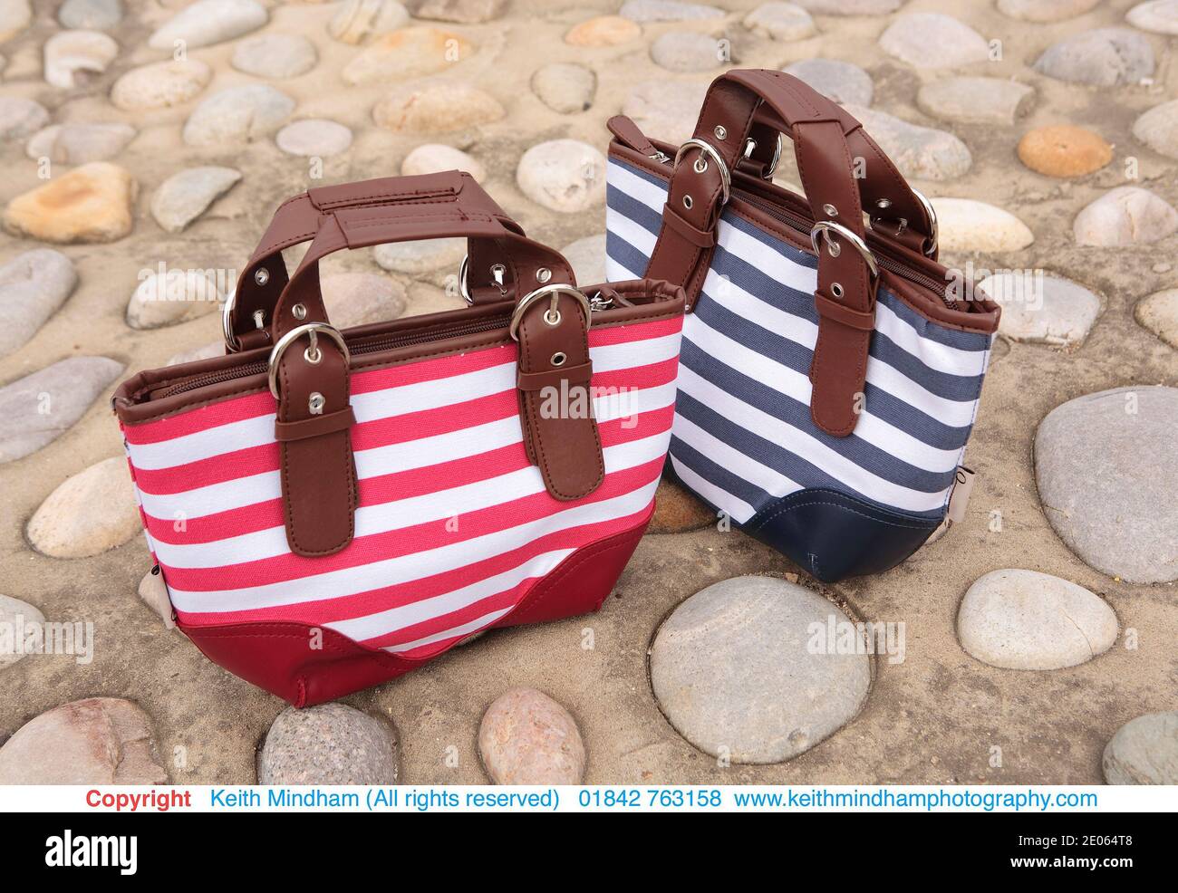 nautical themed red and blue striped ladies handbags on pebble stone path surface Stock Photo
