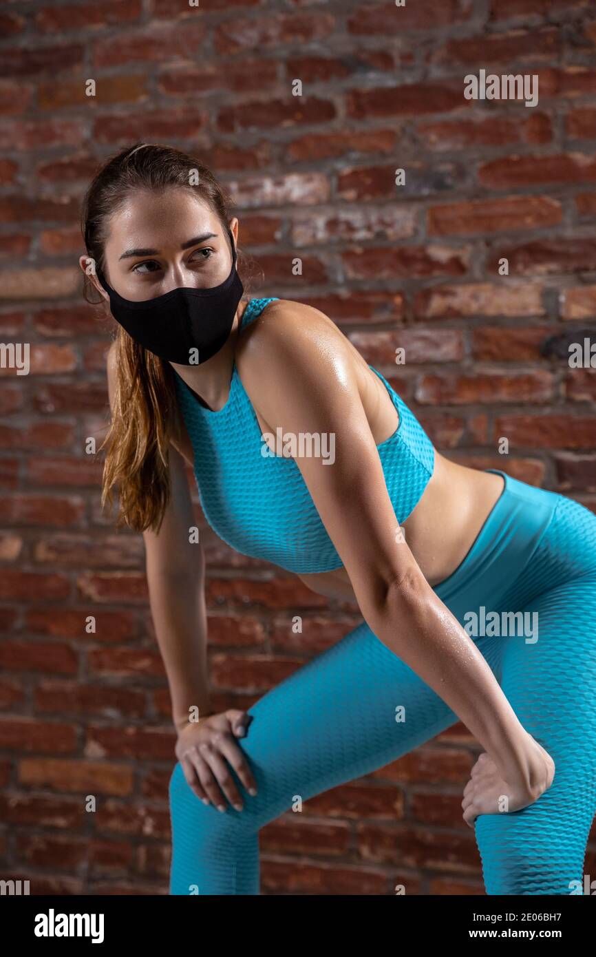 Fit. Professional female athlete training on brick wall background wearing  face mask. Sport during quarantine of coronavirus worldwide pandemic. Young  woman practicing in gym safe using equipment Stock Photo - Alamy