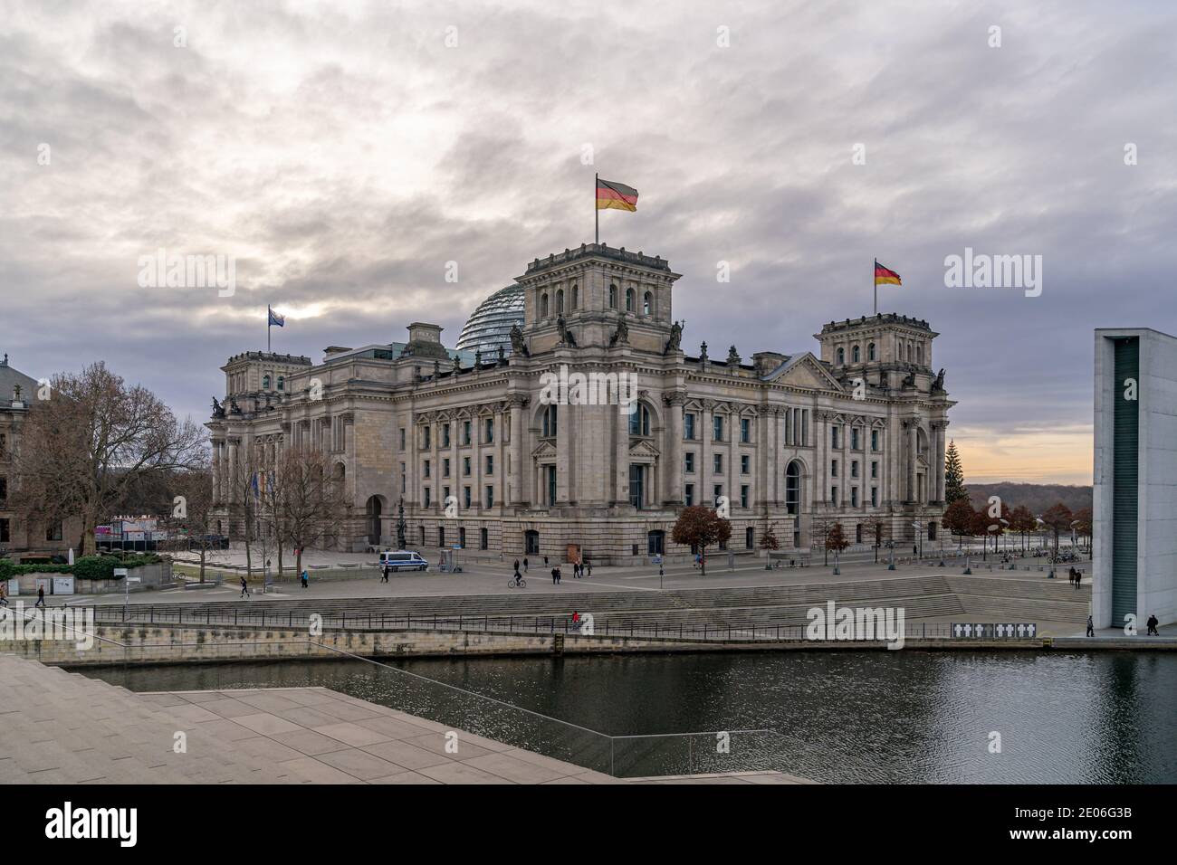 December 28, 2020, Berlin, the Reichstag building by master builder Paul Wallot on the Platz der Republik with flags on the day with cloudy skies. The Reichstag is the seat of the German Bundestag with plenary area. Side view from the Spree side. | usage worldwide Stock Photo