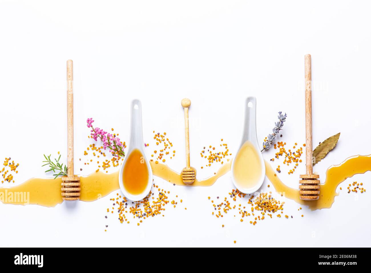 white spoons and honey sticks, with spilled honey, bee pollen and ...