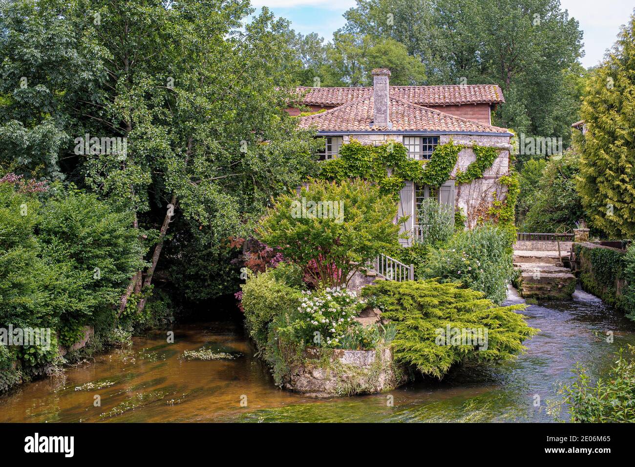 In France, in the village of Bourdeilles, a curious house was built in the middle of the river. It is reached by footbridges over the water. Stock Photo