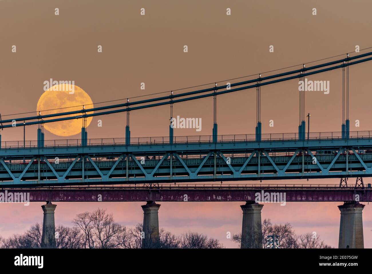 Full moon rising along Triboro RFK suspension bridge New York City East River Stock Photo