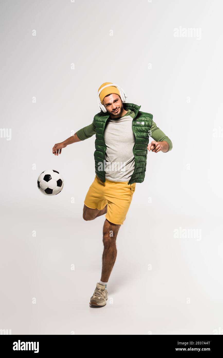 Young sportsman in headphones pointing at camera while playing football