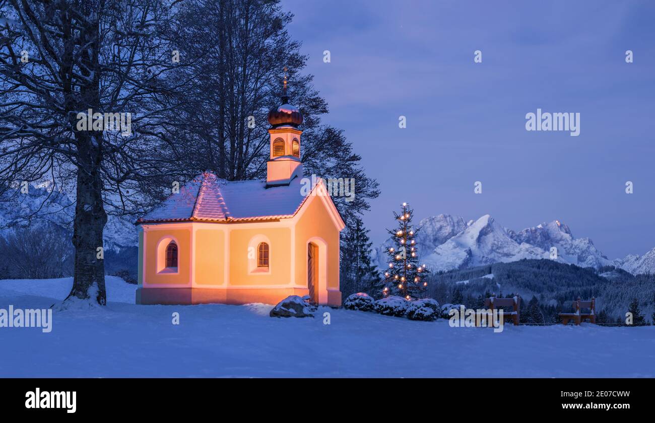 Christmas tree next to beautiful church in the mountains - moonlit night Stock Photo