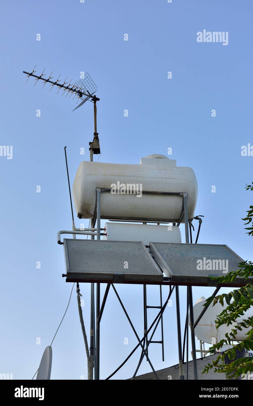 Solar thermal heat collecting plates with how water tank, TV aerial Stock Photo