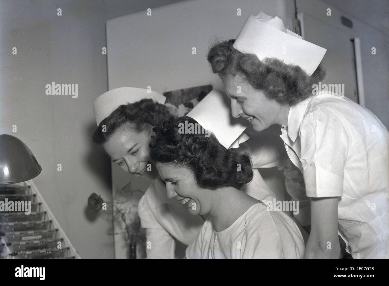 1940s, historical, three nurses in their uniforms and caps of the era in a hospital ward having a chuckle together, USA Stock Photo