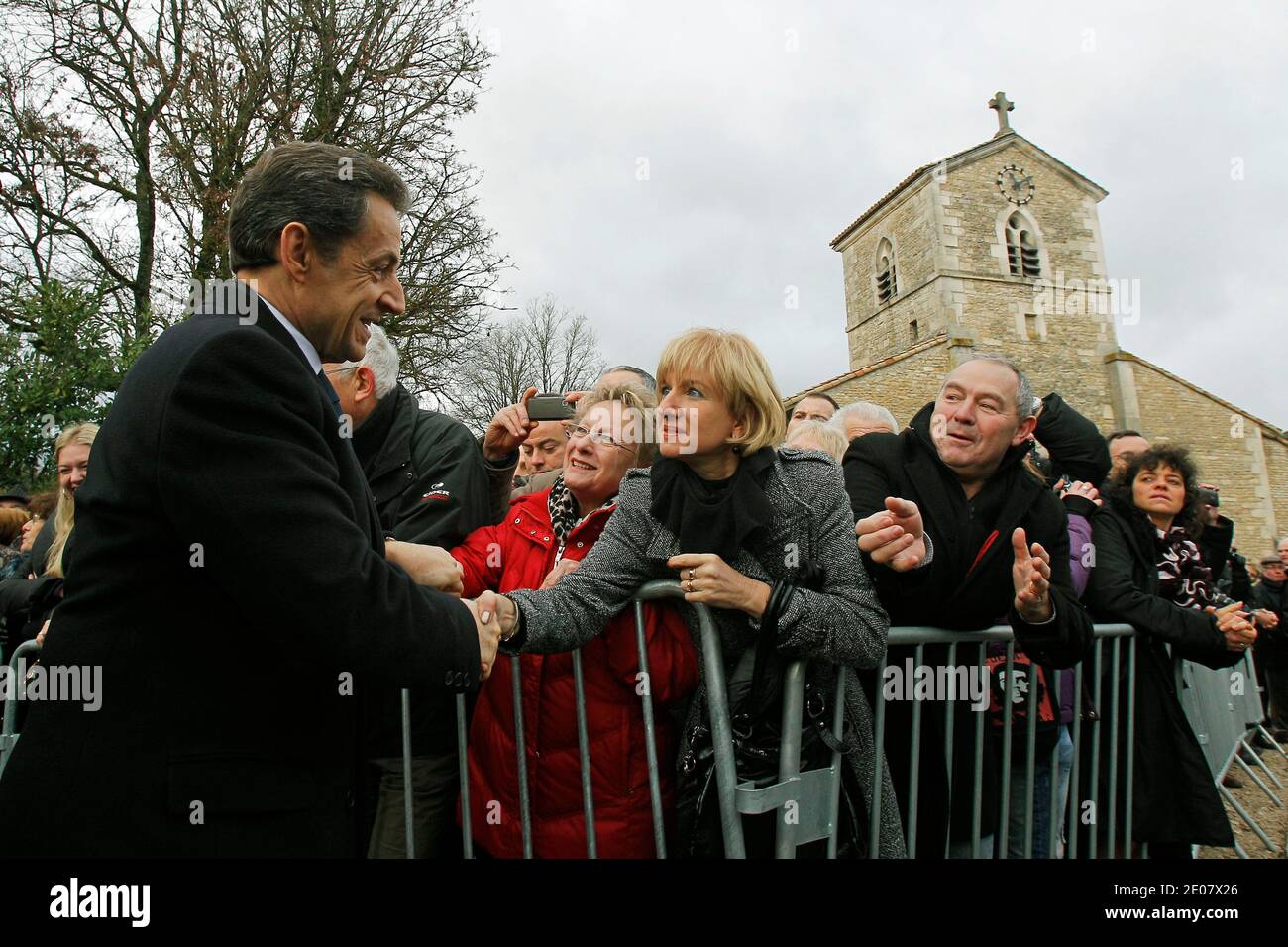 French President Nicolas Sarkozy, shakes hands with bystanders during celebrations of the 600th anniversary of the birth of French heroine Jeanne D'Arc in Domremy, eastern France, on January 6, 2012. Jeanne D'Arc a 15th century Catholic martyr, a teenage peasant who led the French army against the English after experiencing religious visions and was later burned at the stake, has in recent years become a symbol of the populist right. The church Saint Remy where Jeanne D'Arc was baptized in the background.Photo by Michel Euler/Pool/ABACAPRESS.COM Stock Photo