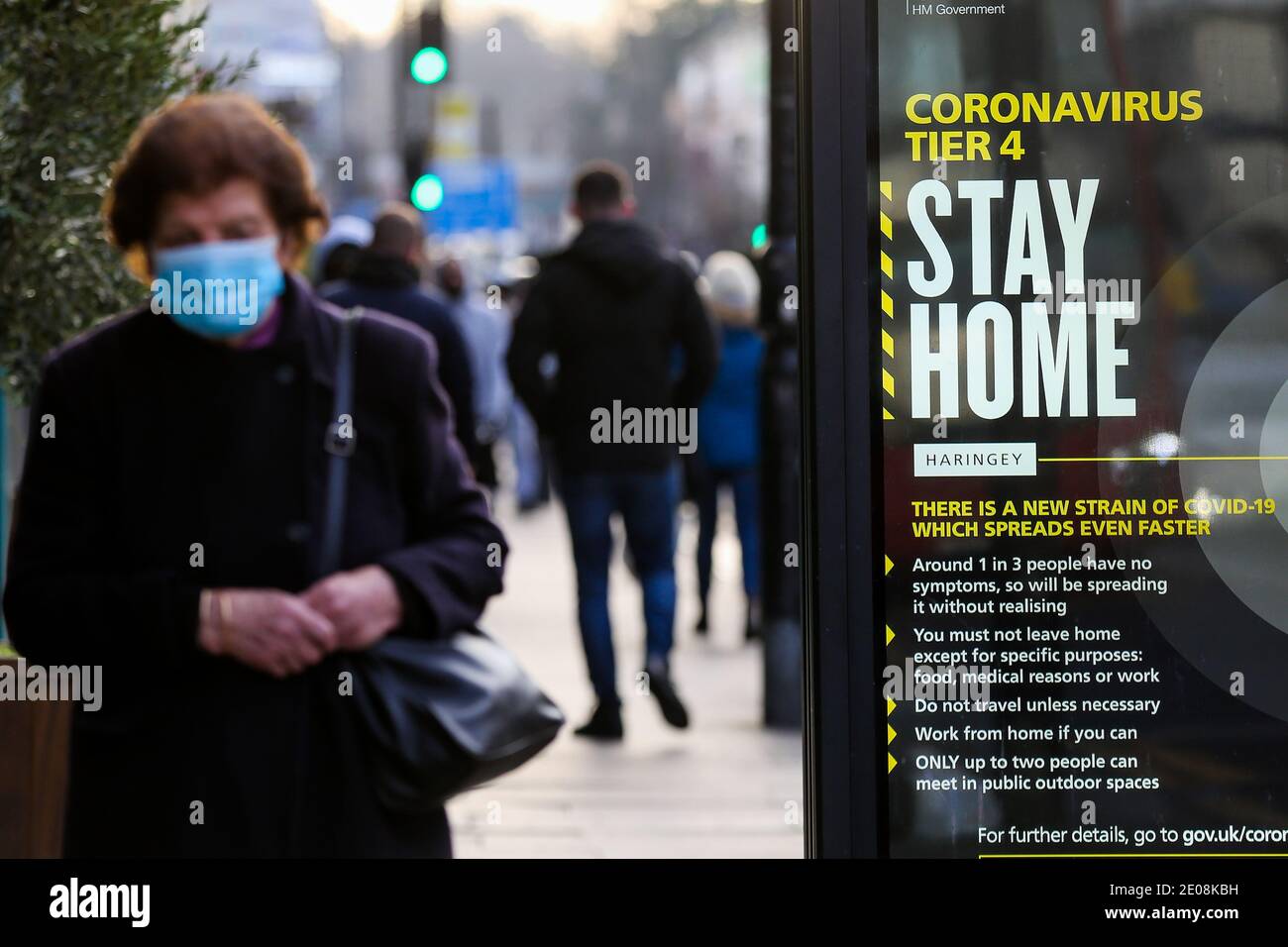 London, UK 30 Dec 2020 - A woman wearing protective face covering walks  past the governmentÕs ÔCoronavirus