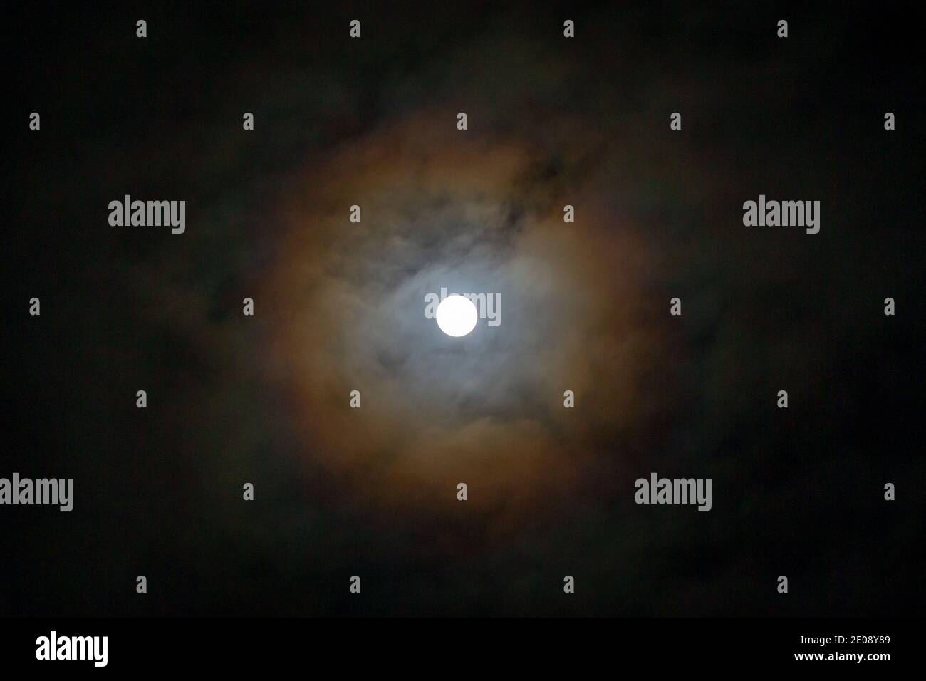 Birmingham, UK. 30th Dec, 2020. The last full moon of 2020 shows a lunar halo of colour in the night sky Halos around the moon are caused by high, thin cirrus clouds, and tiny ice crystals in Earth's atmosphere create the halos that refract and reflect the light. Credit: Peter Lopeman/Alamy Live News Stock Photo