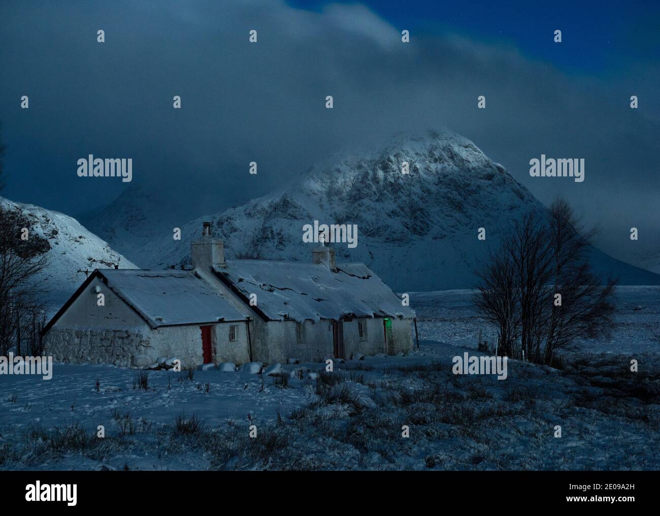 Glencoe, Scotland, UK. 30th Dec, 2020. Pictured: Highland cottage in Glencoe with the famous triangular mountain of Buachaille Etive Mòr in the background with its summit enshrouded in cloud and freezing mist. Yellow snow warning in place as more snow with freezing temperatures expected again overnight. Credit: Colin Fisher/Alamy Live News Stock Photo