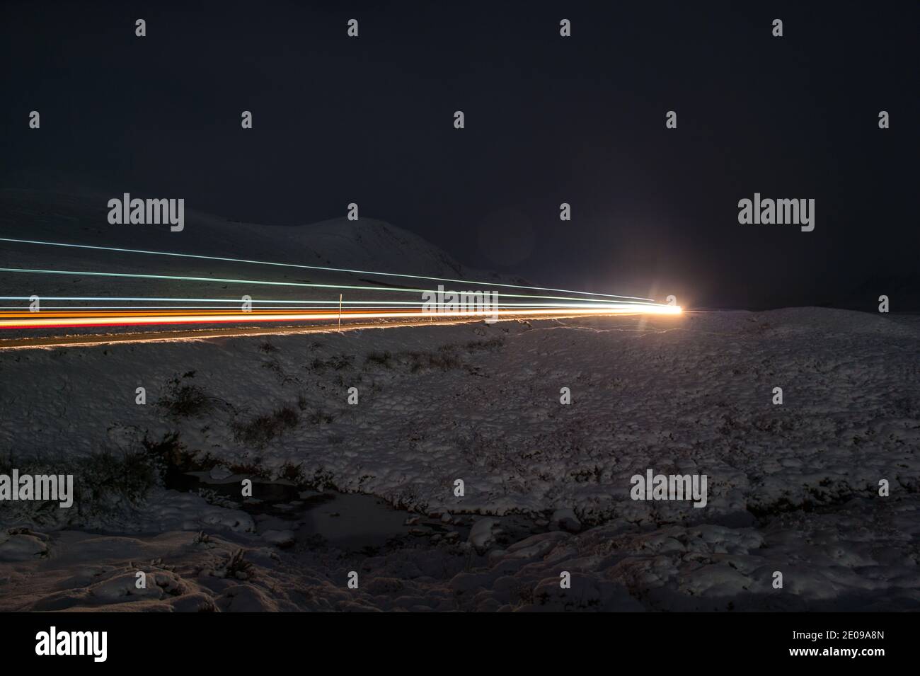 Glencoe, Scotland, UK. 30th Dec, 2020. Pictured: The A82 seen with a solitary vehicle at night under the waning fall moon. The snow reflects back the light causing a dramatic night image. Yellow snow warning in place as more snow with freezing temperatures expected again overnight. Credit: Colin Fisher/Alamy Live News Stock Photo