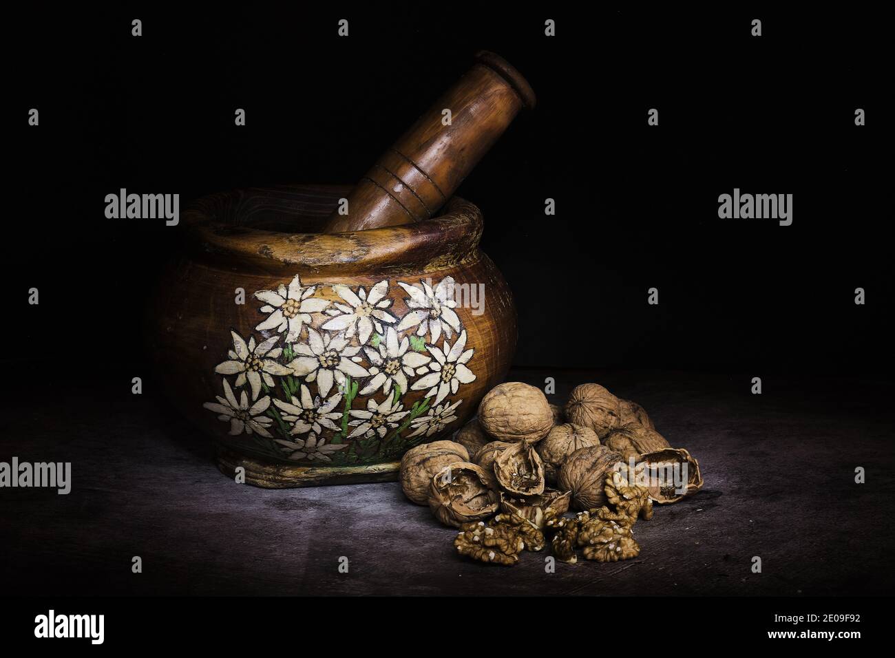 handmade wooden mortar with alpine decorations and nuts to beat Stock Photo