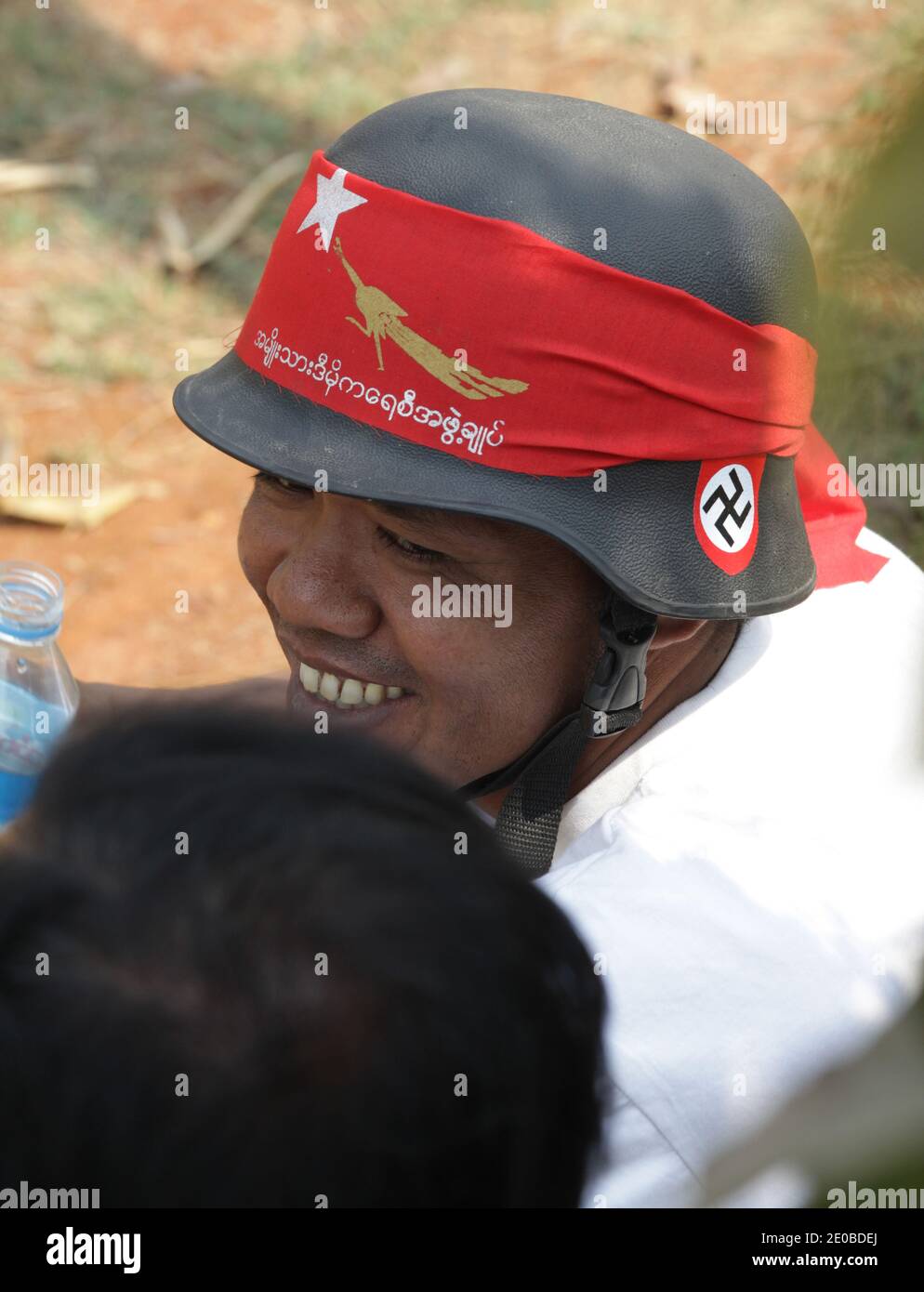 A man wearing a German army helmet with a nazi swastika together with a National League for Democracy red flag is seen among thousands of supporters who gathered for a campaign meeting of Nobel Peace Prize winner and National League for Democracy (NLD) chairman Aung San Suu Ky, in Lashio, northern Shan State, Myanmar on March 17, 2012. Photo by Christophe Loviny/ABACAPRESS.COM Stock Photo