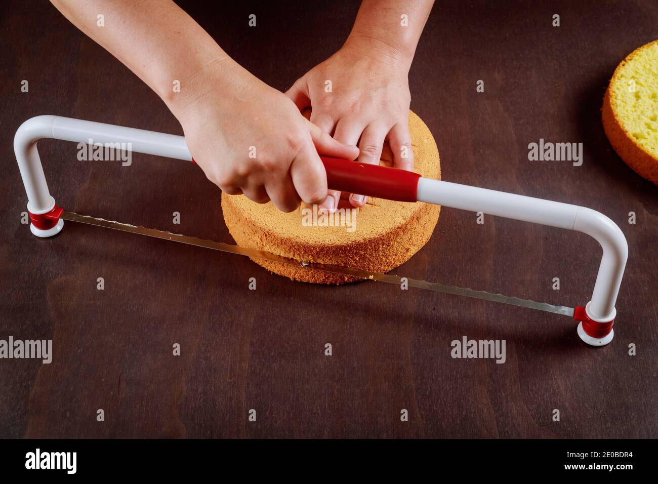 Baker cutting the top of cake with a serrated leveler cake. Making a