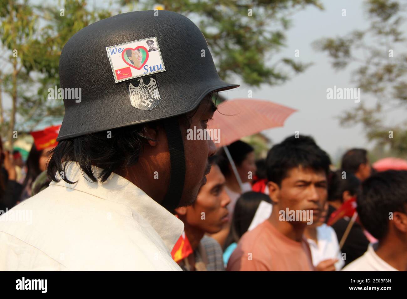 A man with a german army helmet and swastika nazi sign has also a sticker 'We love Suu' . He has no idea who the Nazi were. He is waiting for Daw Aung San Suu Kyi a to give delirious welcome in Lashio, Shan State.. Lashio, Myanmar, on March 17, 2012. Photo by Christophe Loviny/ABACAPRESS.COM Stock Photo