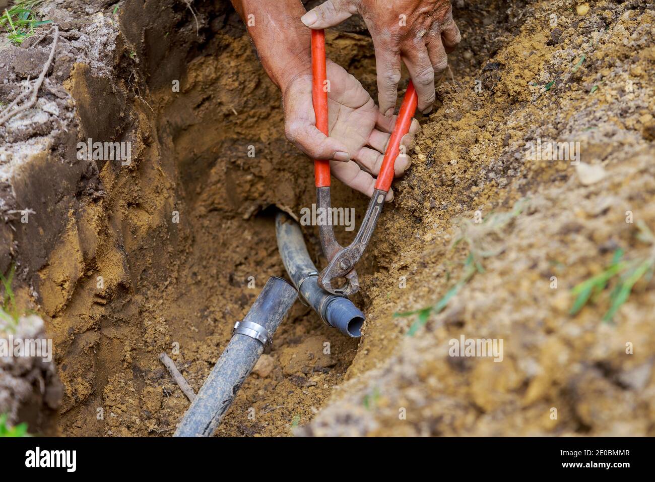 Underground sprinkler system to water the ground in man working with pipes in ground while