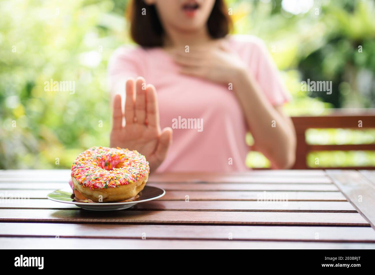 The beautiful Asian healthy middle aged woman sitting on the balcony beside the garden and Refuse to eat the nut. Concept of health care and nutritiou Stock Photo
