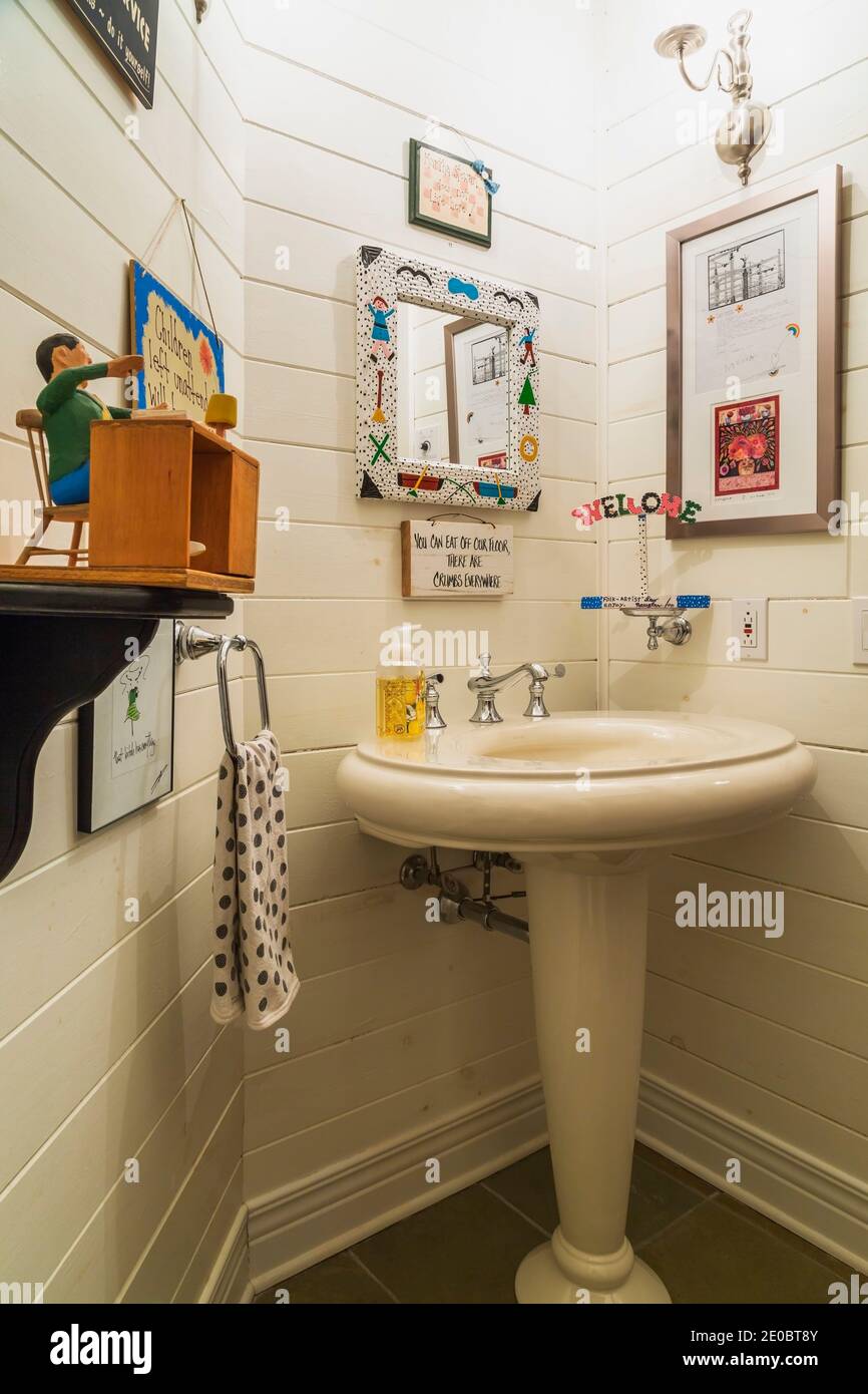 Vintage style pedestal sink and decorative folk art objects in powder room inside contemporary home Stock Photo