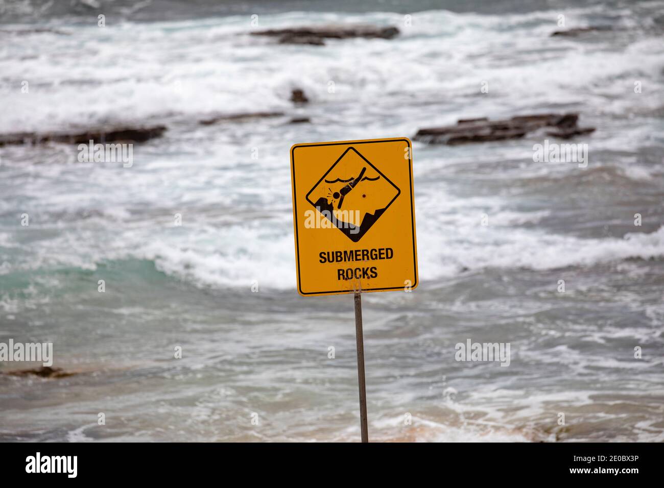 Warning submerged rocks sign advising people not to dive in the ocean,Sydney beach,NSW,Australia Stock Photo