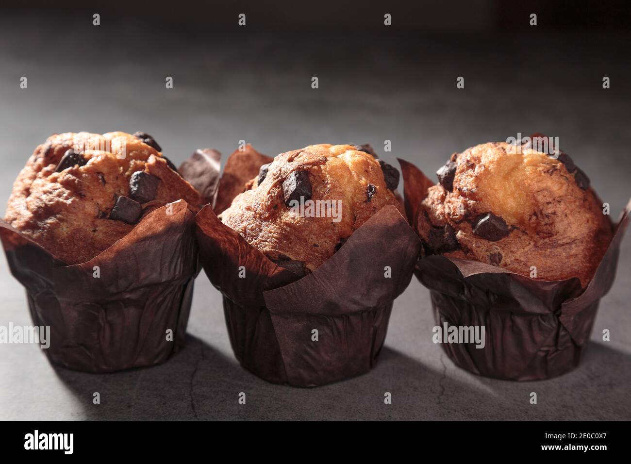 three Chocolate muffins on a dark background. Stock Photo