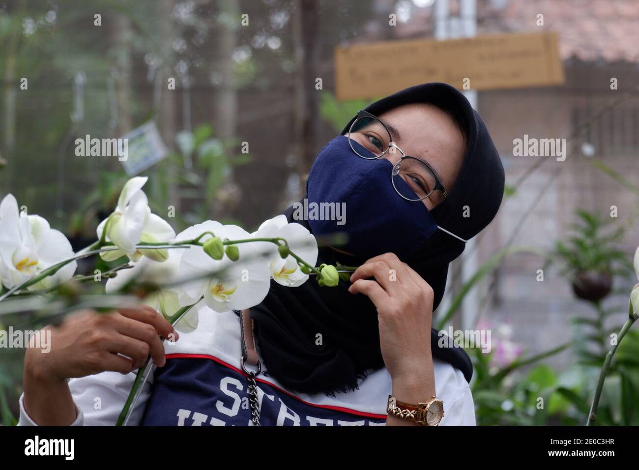Beautiful female tourists who wear hijab visiting flower gardens during the pandemic wear masks to comply with health and safety protocols from COVID Stock Photo