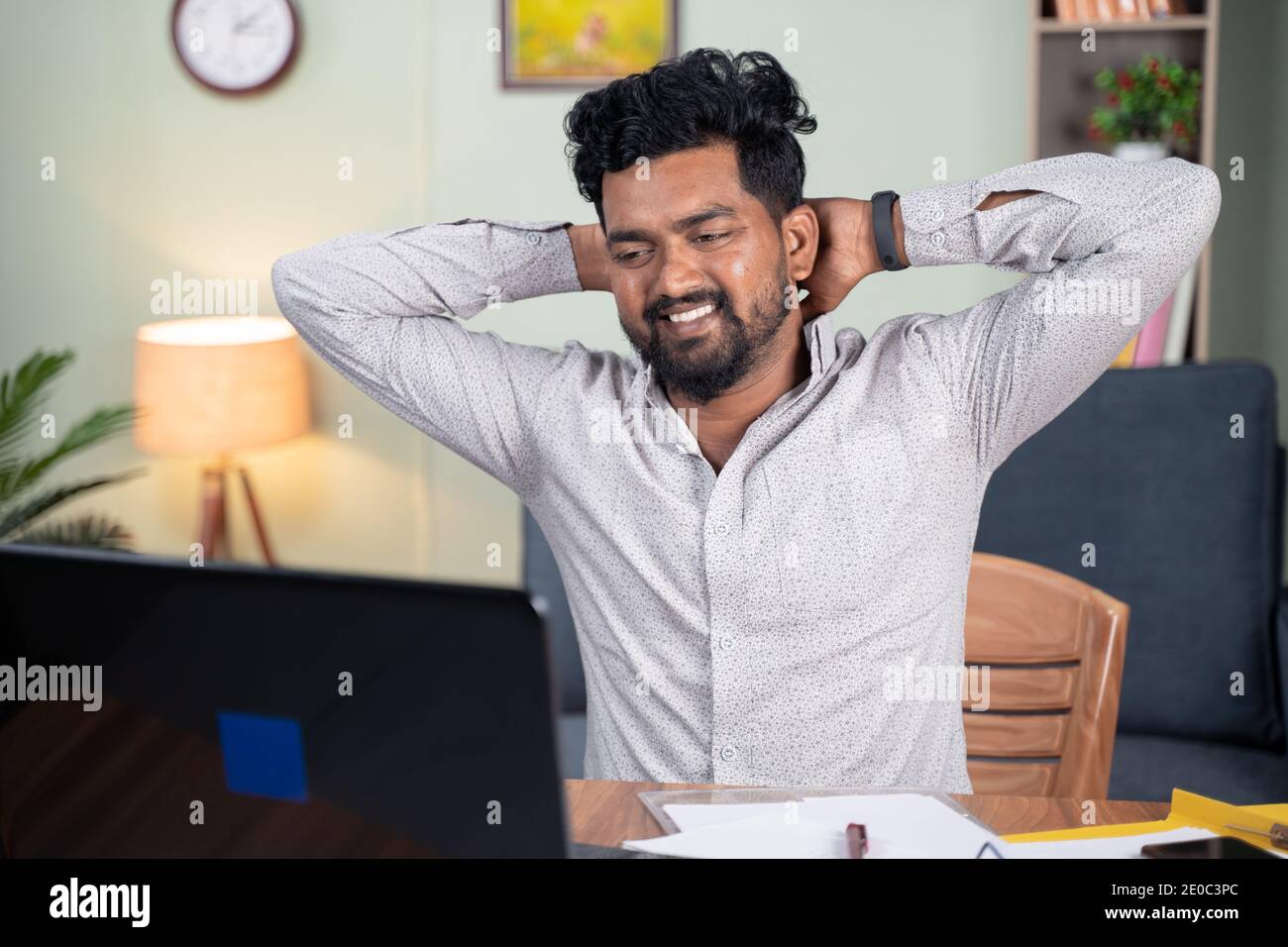 Tired young man feeling relief after completion work by holding hands behind head - Concept of peace, relaxation or satisfaction of finishing work. Stock Photo