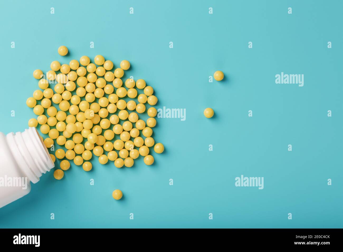 Yellow vitamins in the form of round dragees poured out of the jar on a blue  background. Health concept, dietary supplement, vitamin C. Free space Stock  Photo - Alamy