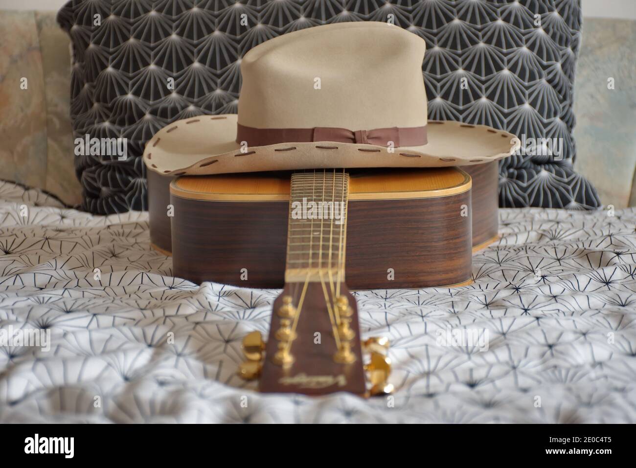 Acoustic folk guitar and cowboy hat on the bed Stock Photo