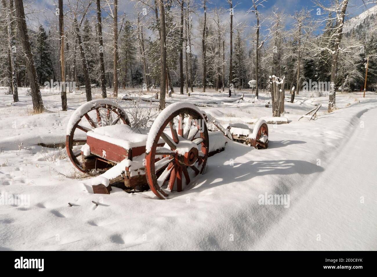 An old, broken snow-covered buckboard wagon along a dirt road, at the lower end of Rock Creek, in Missoula County, Montana. Stock Photo