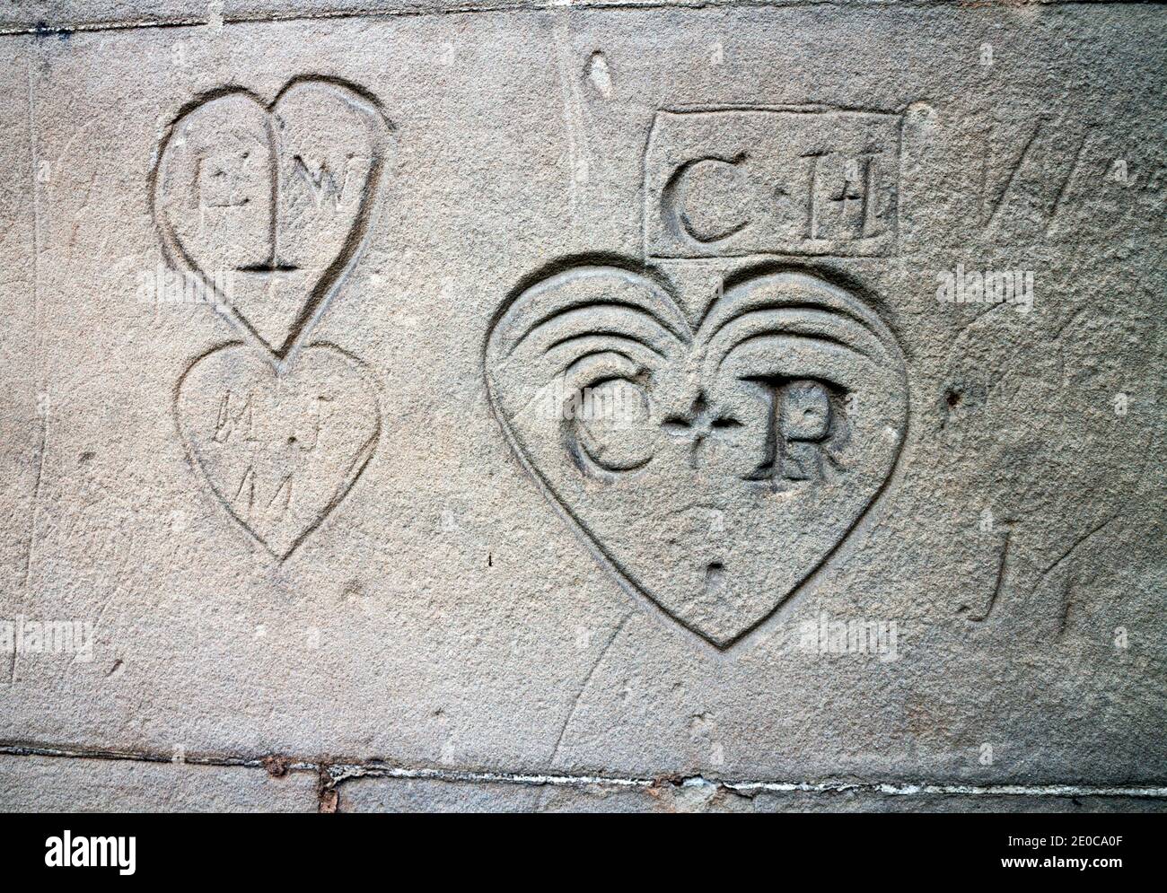 Sandstone wall with carved initials and hearts Stock Photo