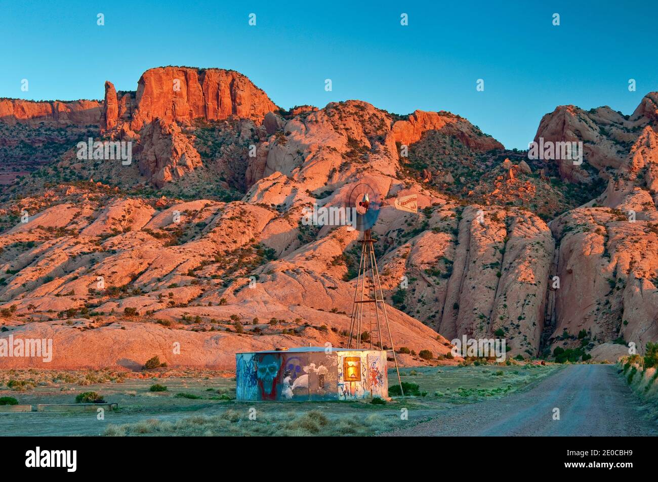 Windmill and water tank, Skeleton Mesa behind, at sunrise, Navajo