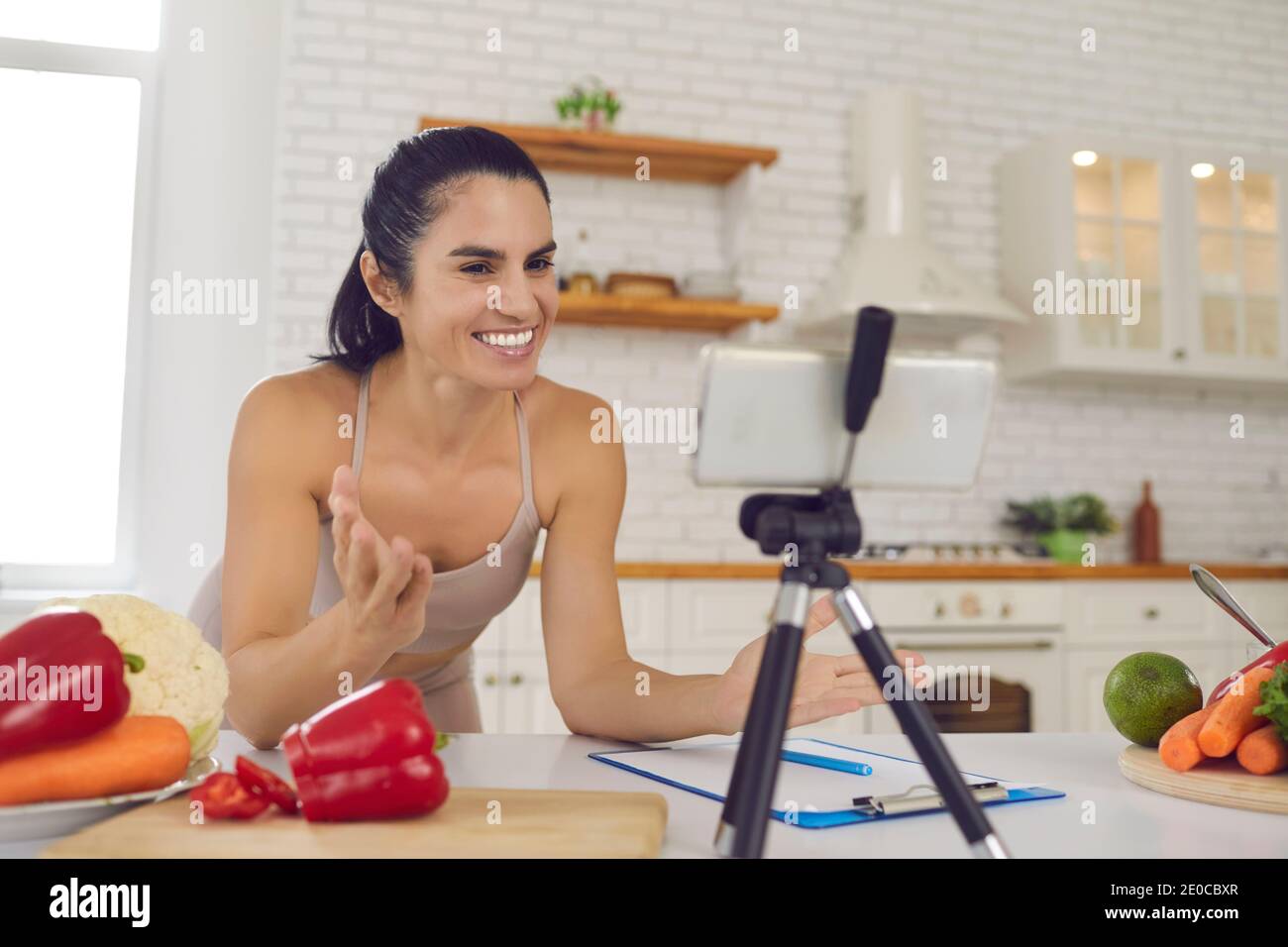 Cheerful fitness vlogger recording video about vegetarian diet and cooking healthy food Stock Photo