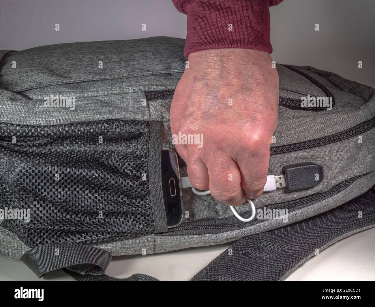 Man's hand connecting a cord / cable between a mobile phone in a pocket on  a rucksack / backpack, and a USB battery charger port fitted into the bag  Stock Photo - Alamy