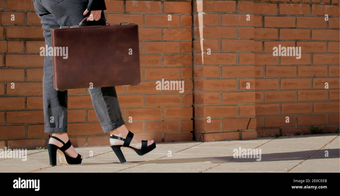 Close up of unrecognizable elegant woman legs in black trousers and heels, walks with a document wallet in her hand, Girl Boss Concept 2021. Stock Photo