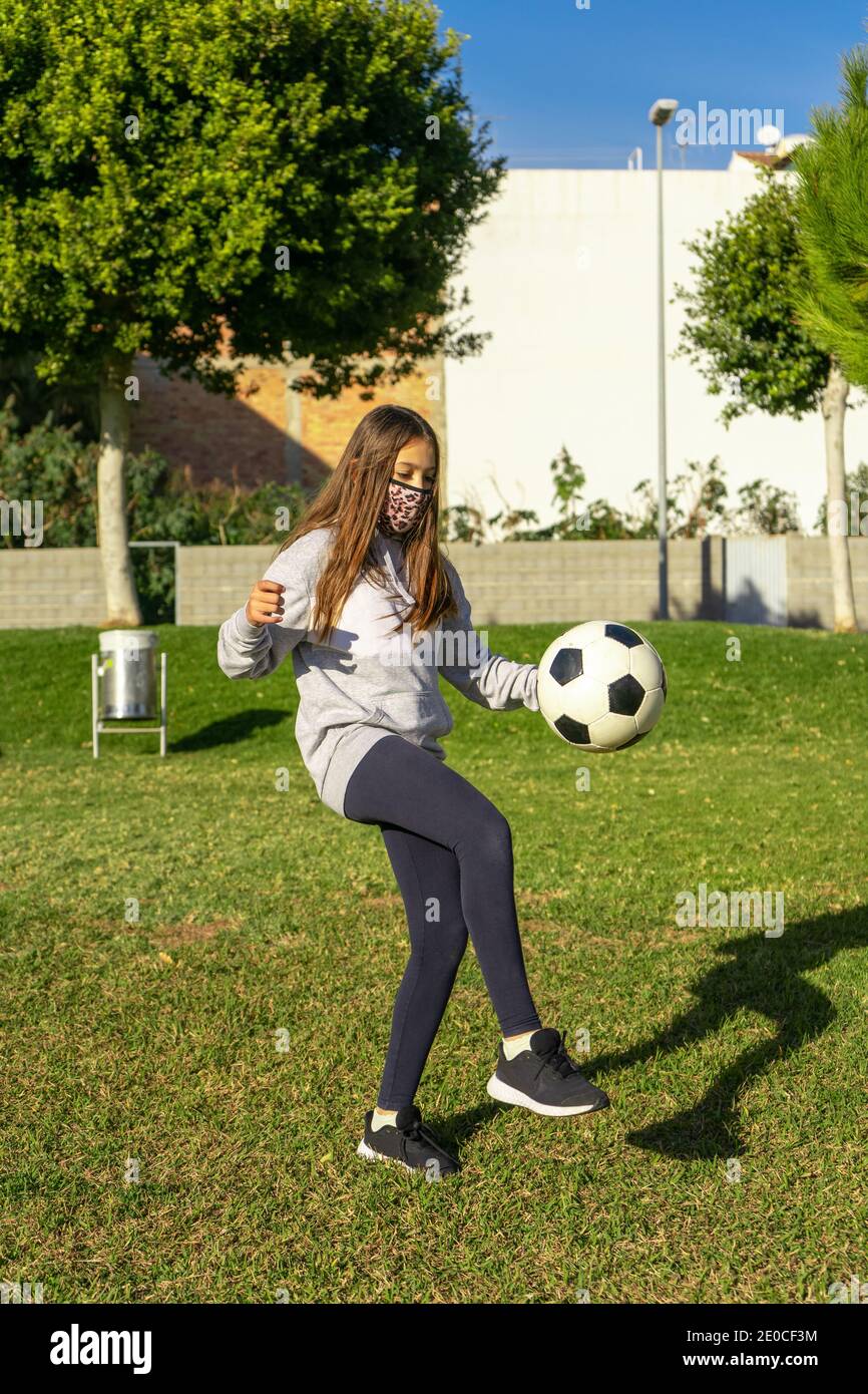 Beautiful little girl playing soccer in a nice park with natural grass ...