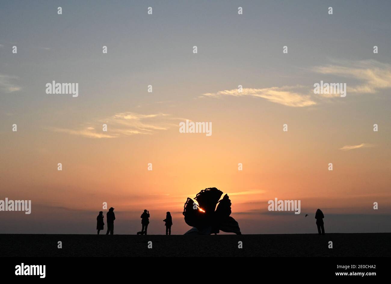 People watching sunrise beside The Scallop, sculpture by Maggi Hambling 2003, commemorating Benjamin Britten, Aldeburgh, Suffolk, England Stock Photo