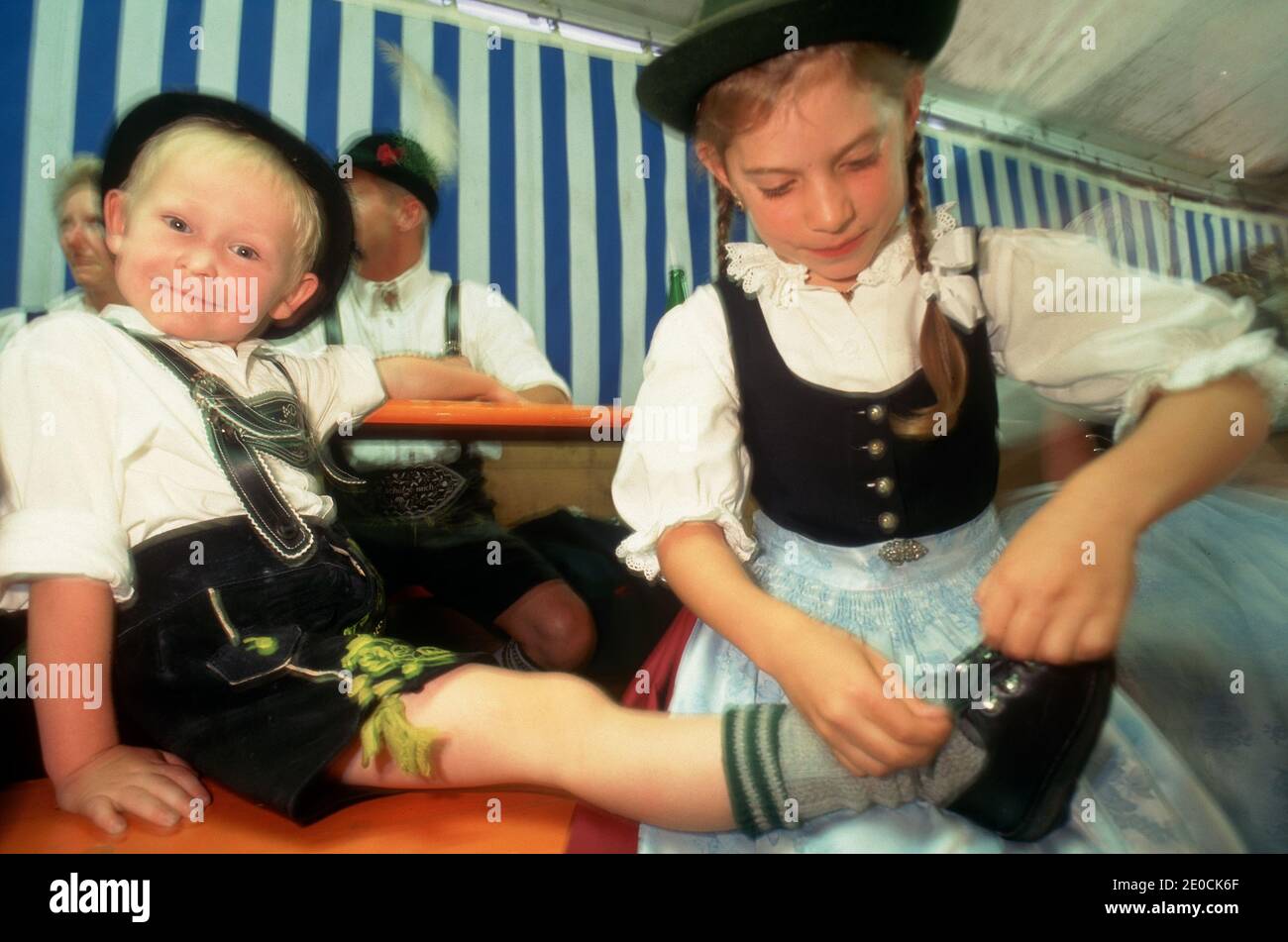 Germany /Bavaria /Young boy in Lederhose is posing with a girl closing his shoe laces . Stock Photo