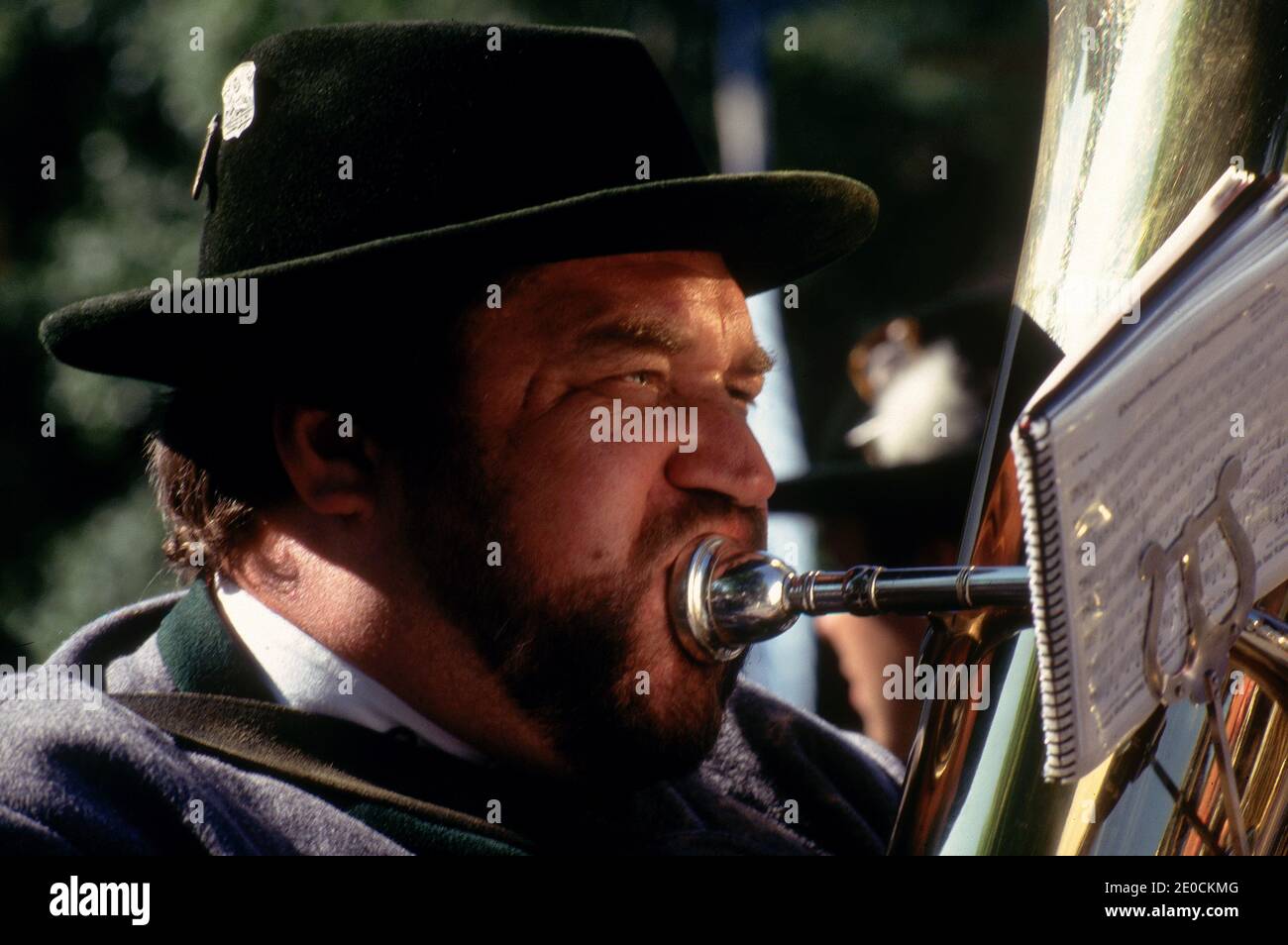 Germany/Bavaria/ Munich/Man in traditional clothes playing a brass tuba ...