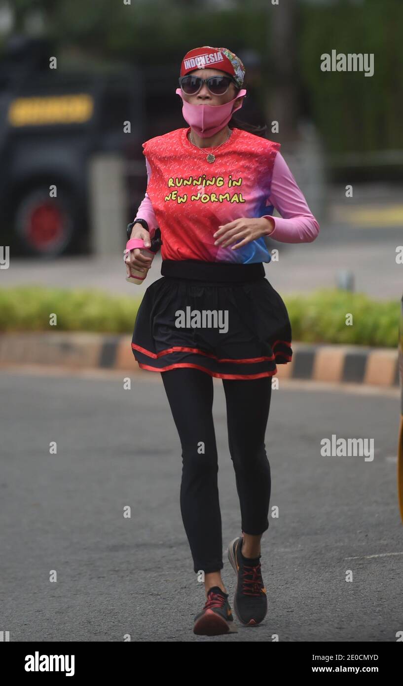 Jakarta, Indonesia. 31st Dec, 2020. A woman wearing a face mask runs on a main street in Jakarta, Indonesia, Dec. 31, 2020. The COVID-19 cases in Indonesia rose by 8,074 within one day to 743,198, with the death toll adding by 194 to 22,138, the Health Ministry said on Thursday. Credit: Zulkarnain/Xinhua/Alamy Live News Stock Photo