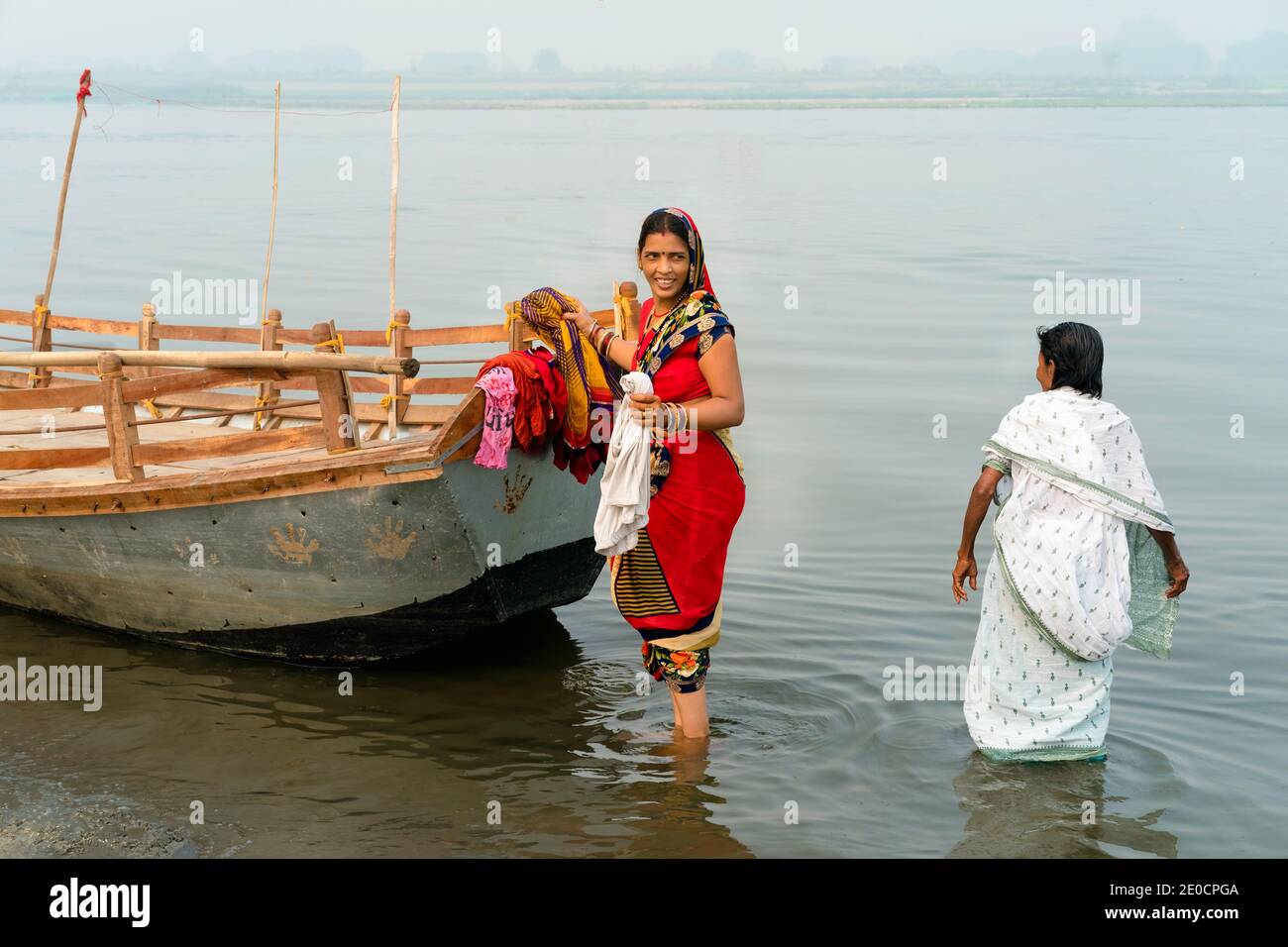 Hindu women devotees in traditional clothes wash laundry in holy river at sunrise in Vrindavan, Uttar Pradesh, India. Stock Photo