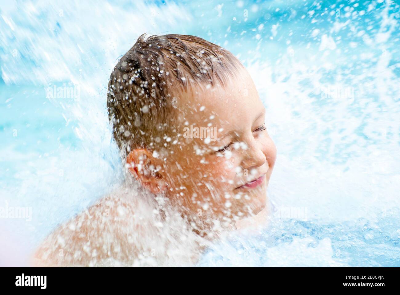 A child boy playing with water in park fountain. Hot summer. Stock Photo