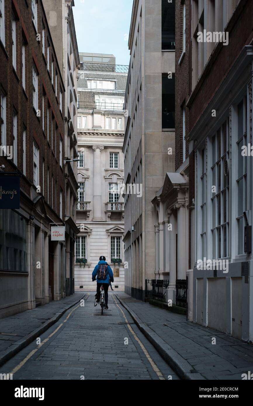 London, UK - December 2020 :  man cycles down a lane in the City of London during Tier 4 lockdown Stock Photo