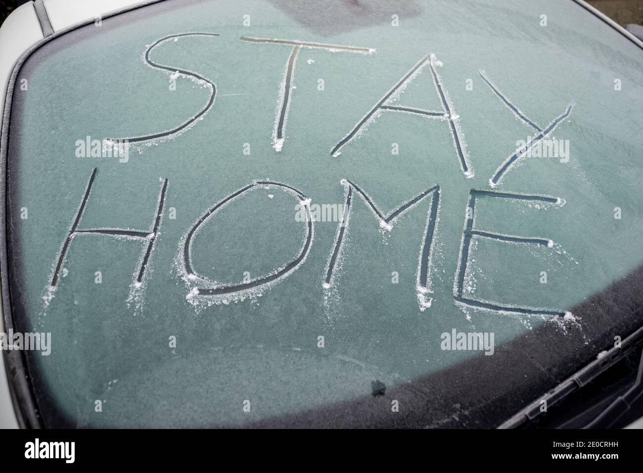 Stay home message written in ice on frozen car windscreen during COVID